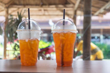 Cold iced tea with lemon and straw, two glass on wood tableの写真素材