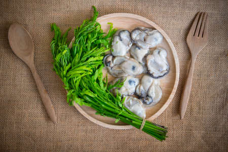 Fresh oyster with vegetable on wood plate, top viewの写真素材