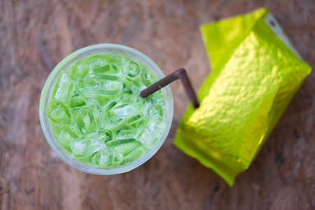 Matcha iced green tea in clear plastic glass with wood backgroundの写真素材