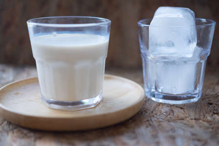 Glass of fresh milk on wooden dish with iceの写真素材