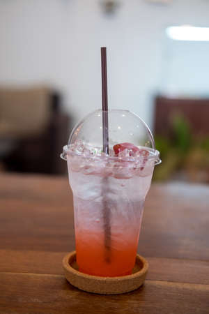 Closeup of strawberry soda in plastic glass on wood table. Fresh summer drinkの写真素材