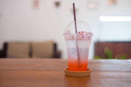 Closeup of plastic glass strawberry soda on wood table. Fresh summer drinkの写真素材