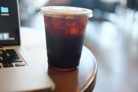 Iced black coffee with notebook ready to work on wooden table (selective focus)の写真素材