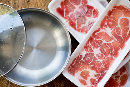 Sliced pork served near hot pot ready to eat