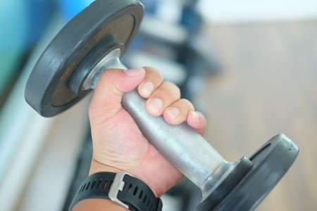 Close up man hand taking iron dumbbells for exercising with it in health clubの写真素材