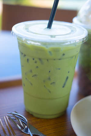 Iced green tea with green drinking straw in a plastic glass