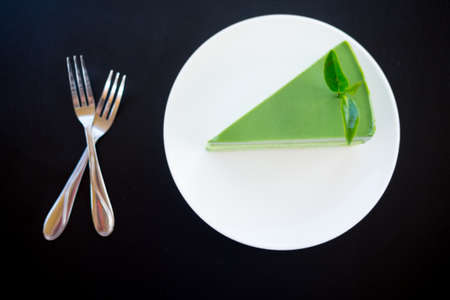 Japanese matcha green tea cake with tea leaf on white dishの写真素材