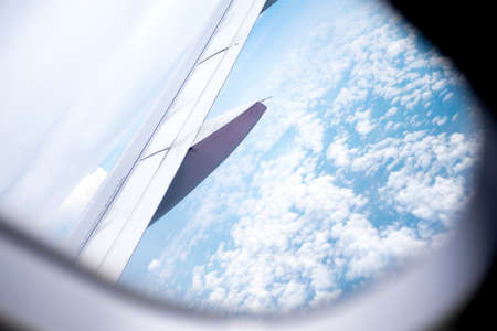 Viewpoint wing of windows airplane flying above the clouds in the skyの写真素材