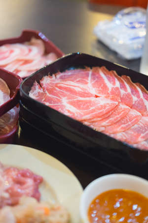 Fresh raw pork slice for grill serving on black tray. Thin slices of porkの写真素材