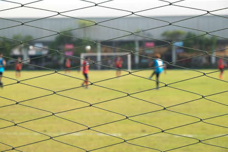 Soccer football net background over green grass or soccer field and blurry stadium and soccer playersの写真素材
