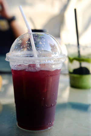 Fruit iced tea in takeaway plastic cup on tableの写真素材