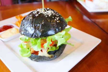 Close up of homemade black burger with cheese. Junk food.の写真素材