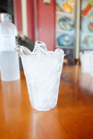 Plastic glass with ice cubes for drinking on wooden tableの写真素材