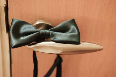 Green bow tie lies on door knob (Groom after wedding)の写真素材