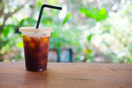 Plastic cup of iced black coffee with blur nature backgroundの写真素材