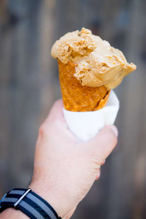 Close up focus of young mans hand holding melting delicious ice cream gelato
