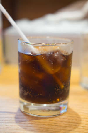 Soft drink glass with ice and tube on the tableの写真素材