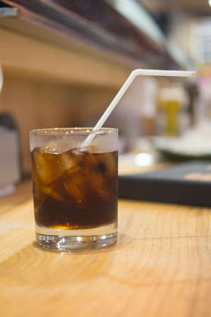 Soft drink glass with ice and tube on the table