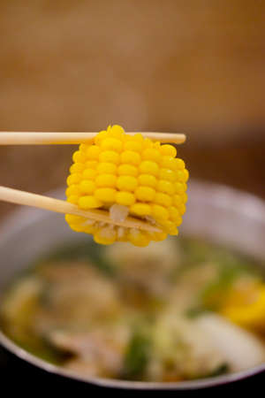 Hand holding corn using chopsticks, Japanese food in restaurant .の写真素材