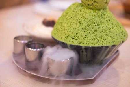 Bingsu green tea with ice smoke on wood table.の写真素材