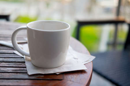Close up white cup of hot coffee on wood table in balconyの写真素材