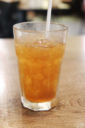 Glass of ice tea with straw on wood tableの写真素材