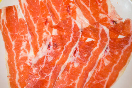 Pieces of raw fresh paper-thin sliced beef for grill to make Japanese yakiniku on plate.の写真素材