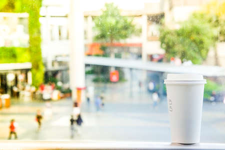 Paper coffee cup with tasty hot coffee on table outdoors with blur focus outdoor public area in thailandの写真素材