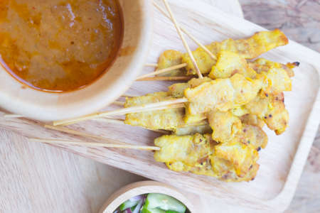 Pork satay. Grilled pork served with peanut sauce on wooden tray. Top view.の写真素材