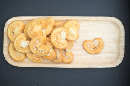 Simple homemade heart shaped cookie in wooden tray on black backgroundの写真素材