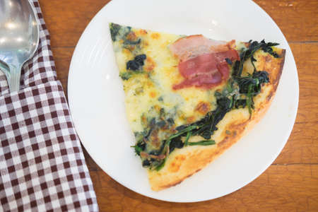 Freshly baked thin crust spinach pizza with baconの写真素材