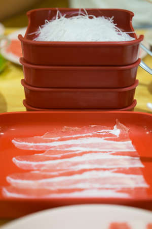 Raw beef and vermicelli in red tray for hot pot on white dishの写真素材