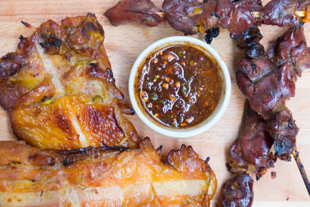 Chicken and liver grilled with Thai style sauce on wooden tableの写真素材