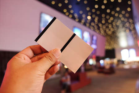 Man holding or showing two cinema tickets (Booking ticket concept)の写真素材
