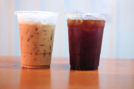 Ice cappuccino and ice black coffee on wooden table