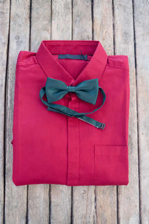 Red shirt and green bow tie on wood tableの写真素材