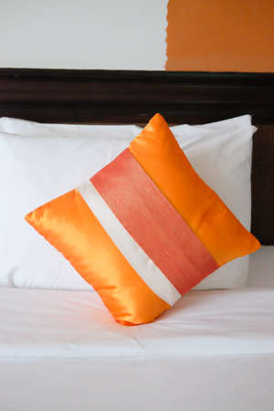 Pillow with luxurious elegant design placing on bed covered with white sheetの写真素材