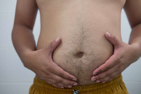Man is holding his too fat tummy (health care and people concept)