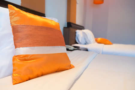 Thai silk orange pillow on white bedの写真素材