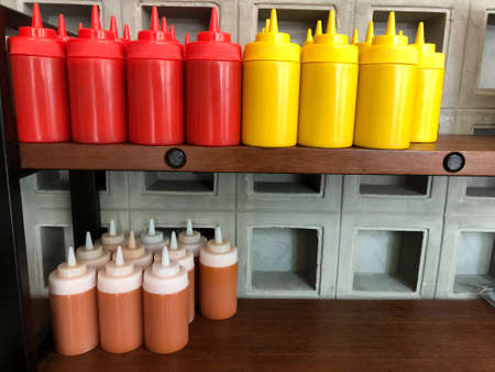 Mustard, ketchup and mayo sauces on wood shelf at restaurant