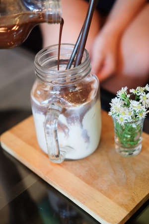 Pours coffee into glass of milk, selective focusの写真素材