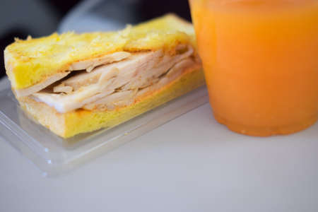 Small meal served in aboard airplane (Sandwich chicken breast with orange juice)の写真素材