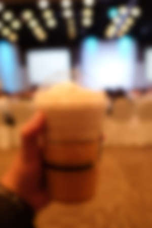 Hand holding cup of ice coffee in the meeting room Blur backgroundの写真素材
