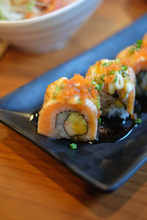 Grilled salmon fish sushi on black dish in restaurantの写真素材