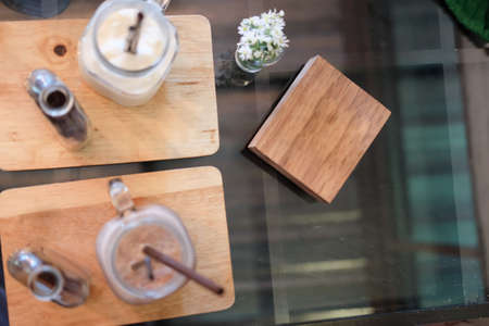 Iced coffee on glass table, top view