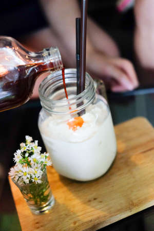 Hand pouring coffee to  to iced milk serving wood trayの写真素材