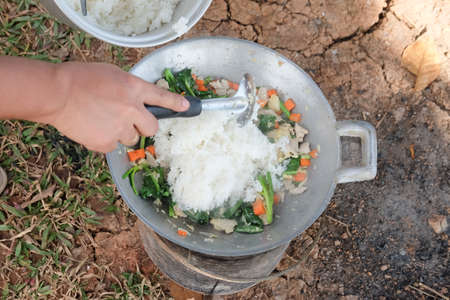 Chef frying rice with meat and vegetable, cooking in rural kitchenの写真素材