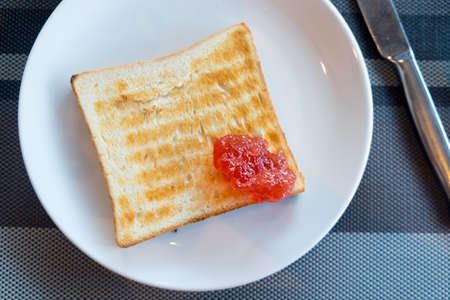 Toasted bread with strawberry jam on white dish