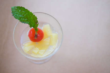 Pineapple juice cocktail with fresh mint and cherry in glassの写真素材