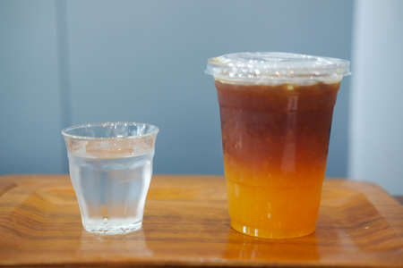 Close up image of a glass of orange cold brew coffee on wooden table